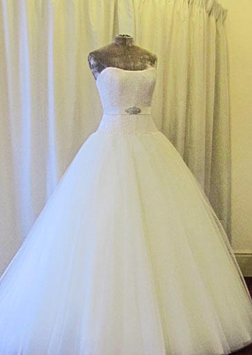This Sassi Holford design features a sleek, belted bodice and full tulle skirt that begins at the hip.