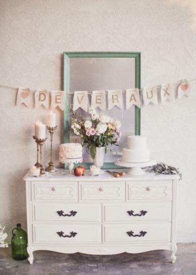 A bridal shower's dessert offerings are displayed on a rustic wooden chest of drawers.