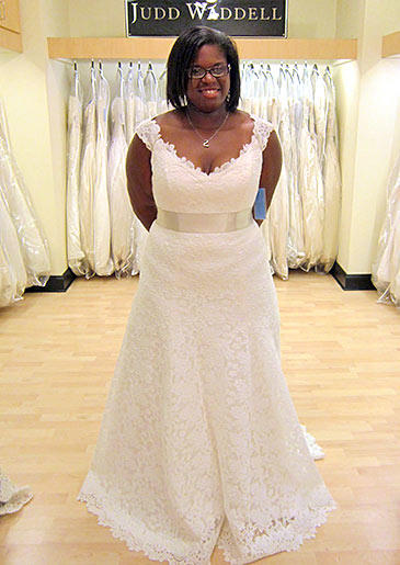 These delicate lace cap sleeves add youthfulness to a formal lace A-line gown with an ivory sash at the waist.