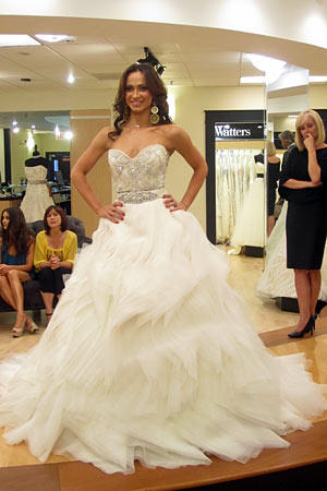 Karina wears Lazaro Style 3153. Fabric: organza with beaded beltDescription: natural waist with ball gown wave skirtColor: ivory with platinum beltPrice: $$$$$