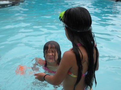 Alexis and Hannah cool off in the pool on a hot day. Spending time by the water at a pool, beach or water park is a great way to play outside without overheating.