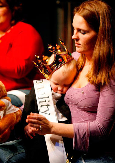 A mother carries a sleepy contestant.