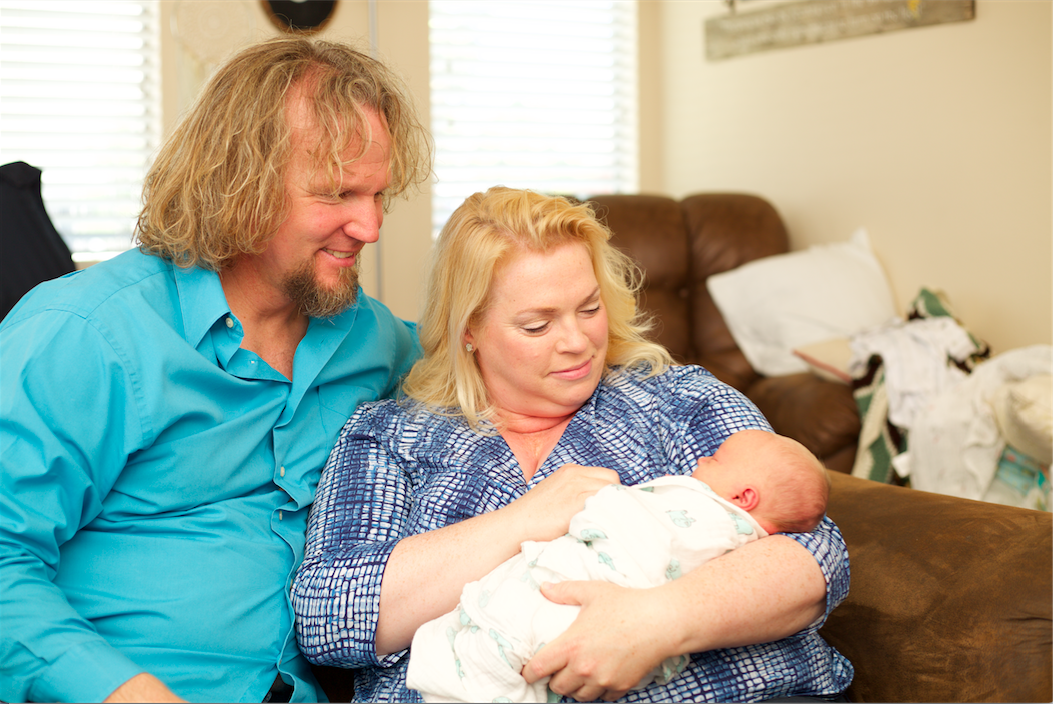 Janelle and Kody Brown hold grandson Axel Brush