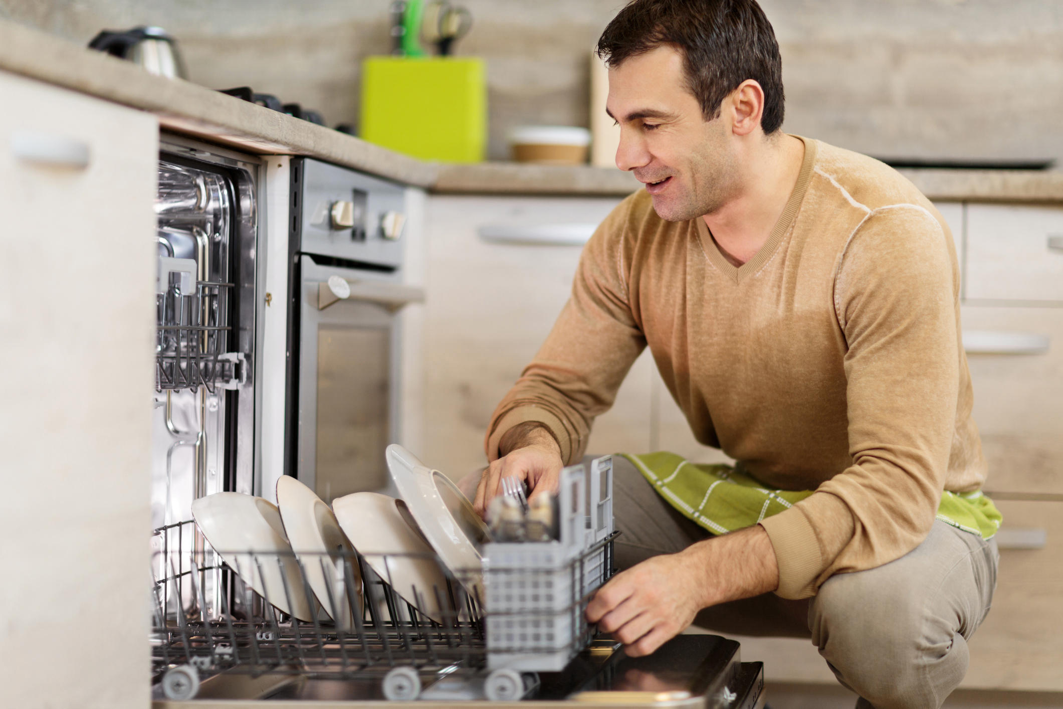 Mid Adult Man Using Dishwasher In The Kitchen Mid Adult Man Using Dishwasher In The Kitchen