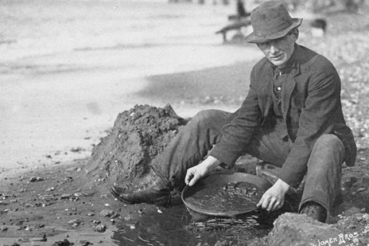 A prospector pans beach sand along the coast of what soon will turn into the boom town of Nome. When gold was first discovered along the shore here in 1899 it was so plentiful that simple panning was the best method for concentrating gold. A 100 years later, underwater miner Zeke Tenhoff has set up his summer yurt home along this