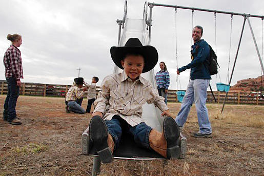 Joel comes down the slide in his cowboy boots at the Dude Ranch.