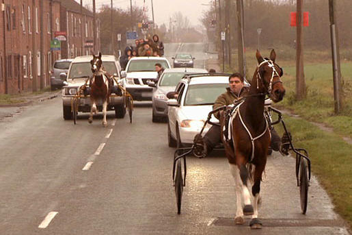 Gypsy men on horses share a highway with cars.