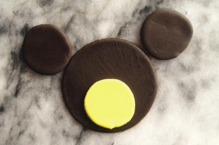 Add two brown fondant circles with diameters of approximately 1 1/2 inches equally spaced above the 3-inch-diameter circle of brown fondant.