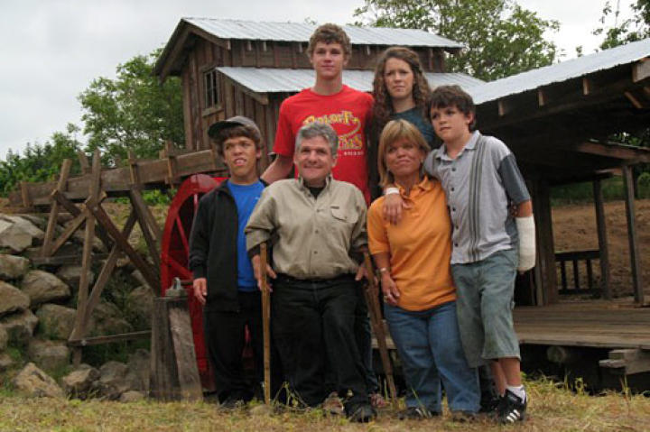 The Roloff Family posing together in front of the farm's saw mill (complete with a 12 foot water wheel).