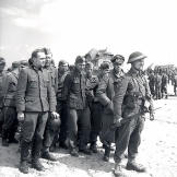 A visibly pleased Canadian soldier stands at the head a group of prisoners (including two officers at the front) who surrendered in Courseulles-sur-Mer, Normandy, on D-Day, June 6, 1944.