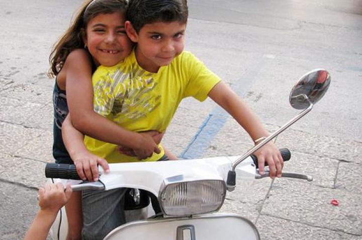 Buddy's kids, Sofia and Buddy Jr., play around on a parked scooter.