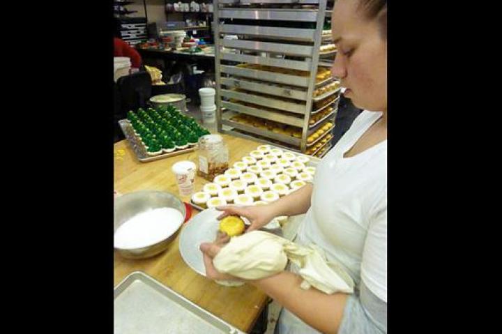 Lauren pipes white icing onto some Christmas cupcakes.