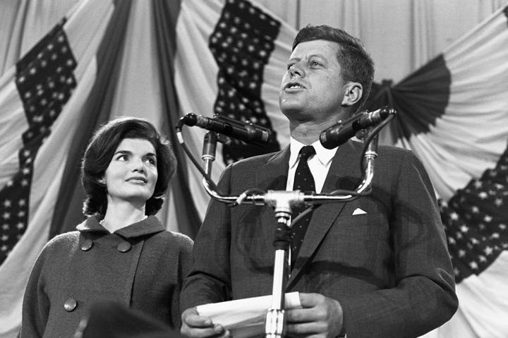 Jackie looks on as her husband delivers a speech.