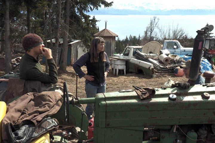 Eivin, Charlotte and Otto stand by one of their tractors as the prepare to drive their cattle out to the head of the bay.