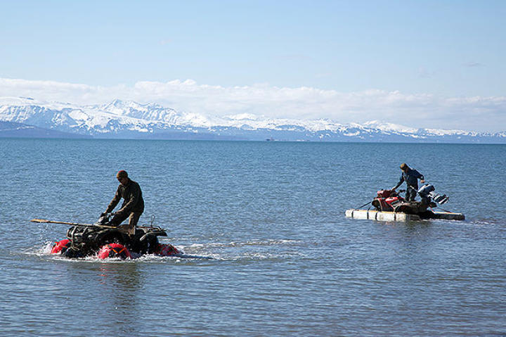 Otto gets ready to try and start his outboard motor on his floating ATV, as Eivin continues to test drive his in the foreground.