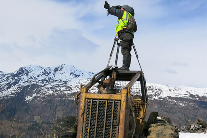 A camera operator filming on machinery.