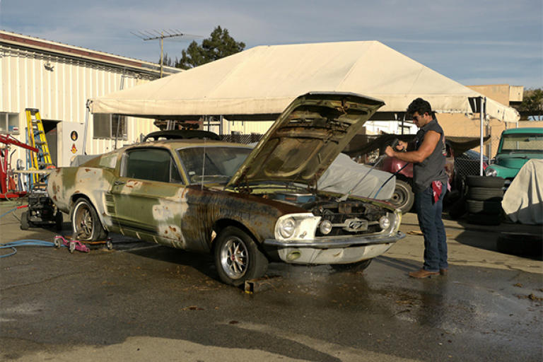 Billy Derian Jr. power washes a 1967 Ford Mustang.