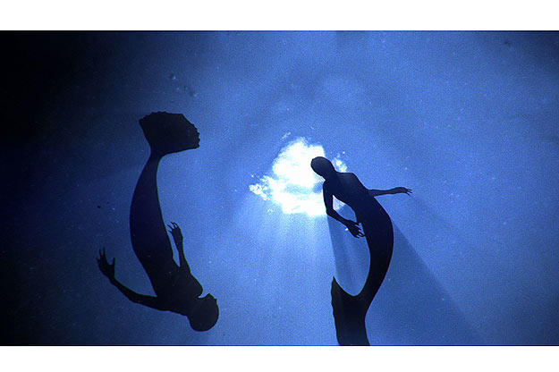 Mermaids swimming through the deep ocean.