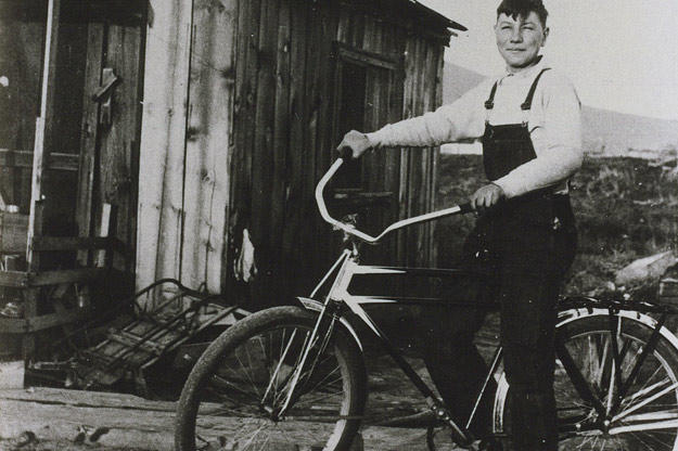 John shows off the bike he bought in 1933 with his earnings from delivering newspapers. John also made money selling used bottles to bootleggers. He collected the bottles in the alleys of Klamath Falls (an early recycler!) and sold them for a penny apiece. Sometimes he could make as much as 15 cents a day!