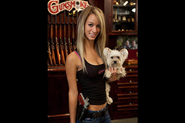 Paige poses in the Gunsmoke shop with two of her favorites: her dog Malibu and the Colt Defender on her hip.