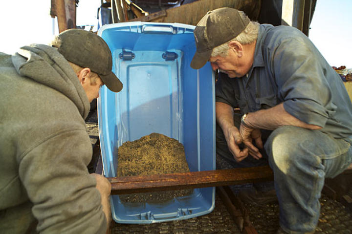 Owner Steve Pomrenke smiles at rich gold-laden sediment extracted by the vessel's wash plant. This sediment will be taken ashore for further concentration.