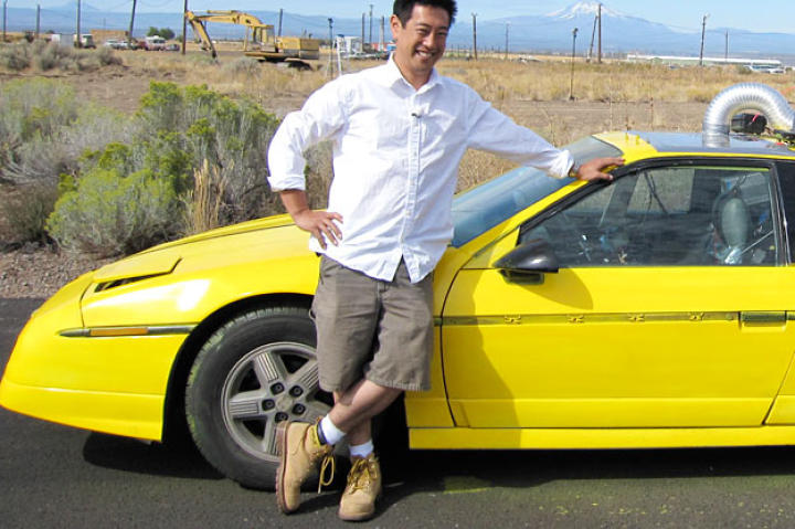 Grant Imahara poses with the remote-controlled car he built to test whether a speeding vehicle can truly skip across a water's surface, as seen in