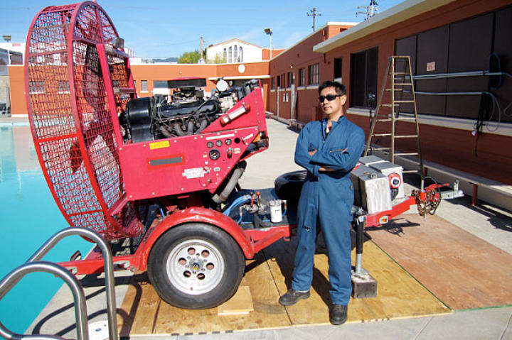 Grant Imahara poses with the giant fan used to simulate the pressure of helicopter winds, part of the Cliff Hanger myth test. How long could a hero truly cling to a helicopter before being rescued?