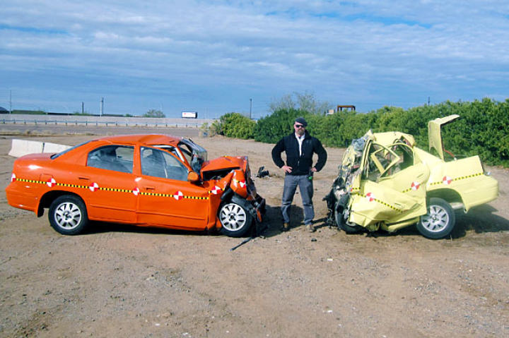 Is the force of two cars crashing into each other at 50 mph the same as one car crashing into a wall at 100 mph? Nope. Jamie Hyneman stands before the evidence.
