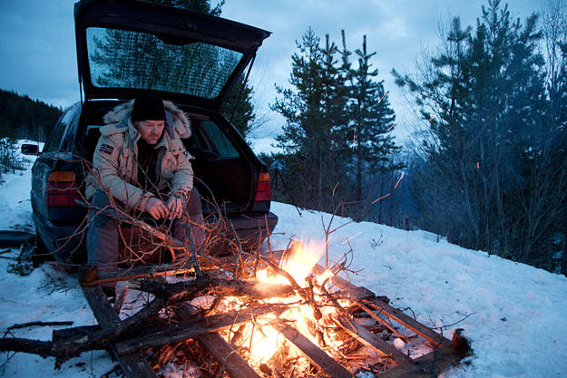 Les Stroud warms by a fire in the Norwegian mountains.