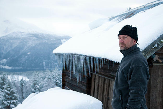 Les Stroud in front of a modest shelter in the extremely cold Norwegian weather.