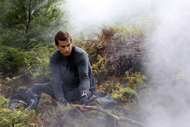 In New Zealand, after using his cell-phone battery to start a fire, Bear Grylls takes a minute to warm up.