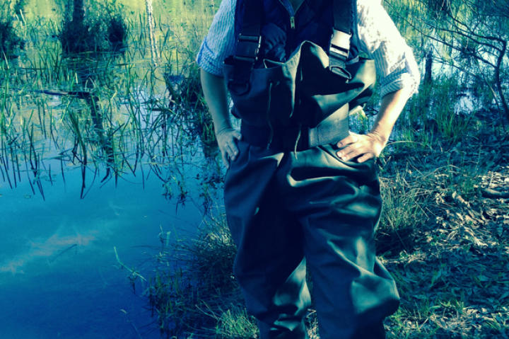 After watching the DP and crew don waders to shoot from the water on various shoots I decided I had to experience the joy of actually getting into the dark cold swampy waters. Of course all the waders were a man’s size L and I’m barely a 5’2 female, but no mind. Given they were like 5 sizes too big, I was more worried about tripping over myself just walking to the waters edge, but then I heard about a far more dangerous threat – snapping turtles. One of the camera assists said they could snap a bone in two in seconds. Awesome. I took one step at a time trying to feel my way through all the roots, logs, and algae. As I got deeper, the mud became like squishy clay, which emitted the most foul odor. I finally made it out to where the rest of the crew had set up the very expensive camera. I watched the scene unfold with one eye on the actors and the other on the water. Bucket list – wading in the swamp – check!
- Ashley Crary, Show Runner