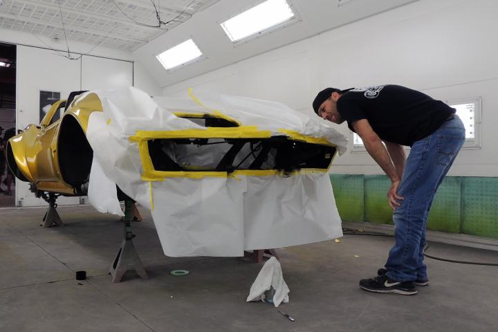 Jason Aker surveys the 1968 Gold Corvette during its exterior transformation from black to gold.
