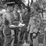 MPs question a (literally) dirty German prisoner who was found to be carrying a large quantity of Russian cash, Normandy, July 1944.