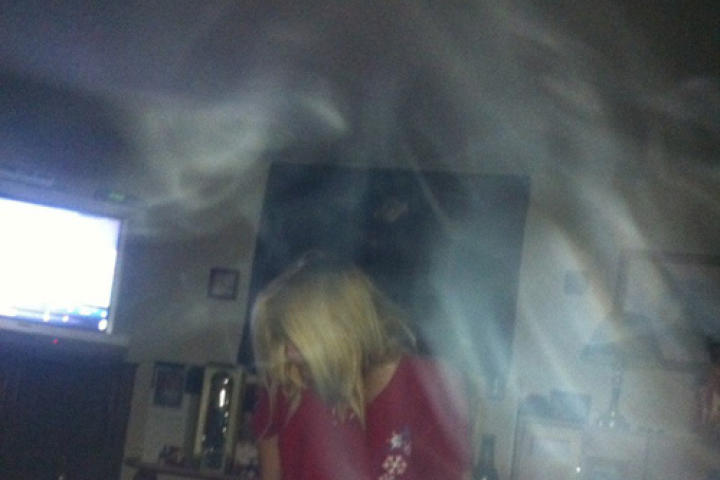 This is a picture of myself- it’s in my bedroom. It was taken at 7am in the morning. I was getting something out of my trunk at the end of my bed. My boyfriend thought it would be cute to snap a picture of me so early and knowing I’d be mad for doing so and this is what came in the picture. It’s not smoke we don’t smoke in our house. I have other pictures in same room with orbs and other things as well.The TV was on to the left also.
-Brenda