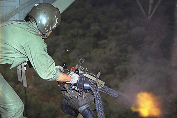 An amazing image showing a U.S. Air Force Sikorsky HH-53E helicopter crewman firing a M134 mini-gun during rescue patrol over South Vietnam.