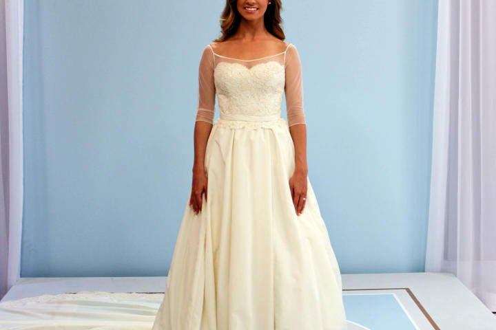 Olivia Kate was stunned by the gorgeous results of Kelly's efforts. She said she'd be wearing this beautiful ball gown with box pleats and off-the-shoulder illusion net sleeves. The cost to remake this dress was $875.