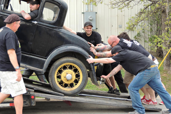 Tony Taylor observes as KC Mathieu, Mike Coy, Dustin DeLeon and Josh Anderson steady the Model A as it comes off the trailer.