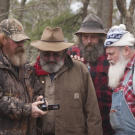 Trapper, Huckleberry and Jeff look on as a local resident shows video evidence of a monster sighting.
