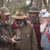 Trapper, Huckleberry and Jeff look on as a local resident shows video evidence of a monster sighting.