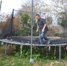 Scott Menaged bounces on a trampoline while partner Lou Amoroso looks on.
