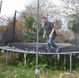 Scott Menaged bounces on a trampoline while partner Lou Amoroso looks on.