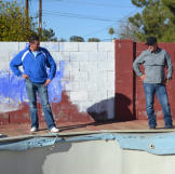 John Ray and Jace Johnson look at a pool in poor condition at a newly purchased property.
