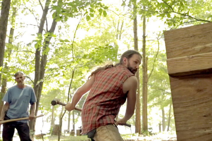 Spencer takes a crack at breaking up some wood while Eugene looks on.