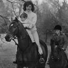 On Nov. 19, 1962, Jackie holds John as she rides a horse at the Kennedy estate in Middleburg, VA. Caroline follows Mom and baby brother on her pony, Macaroni.