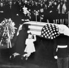 Jackie and her daughter Caroline kneel before John F. Kennedy's coffin.