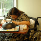 Olivia, still relying on oxygen for breathing, sits in her hospital room doubled over in pain.