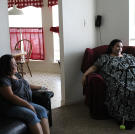 Olivia sits in her brother's living room after her daily exercise. In addition to walking around the neighborhood, she must go up and down a flight of stairs each time she enters and leaves the guest bedroom.