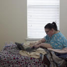 Penny uses her laptop from her bed at the temporary apartment in Texas.
