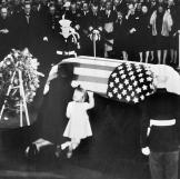 Jackie and her daughter Caroline kneel before John F. Kennedy's coffin.